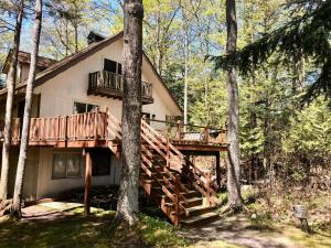 una casa con una terrazza in legno nel bosco di East Beach Retreat a Omena