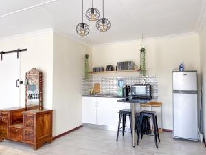 a kitchen with a refrigerator and a table with stools at Cozy Cottage in Langebaan