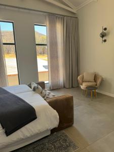 a bedroom with a bed and a chair and windows at De Marea villa in Naboomspruit +26 photos