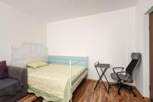 een slaapkamer met een bed en een stoel bij Stone Gate Apartment #2 in Boekarest