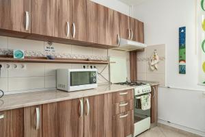een keuken met houten kasten en een magnetron bij Stone Gate Apartment #2 in Boekarest