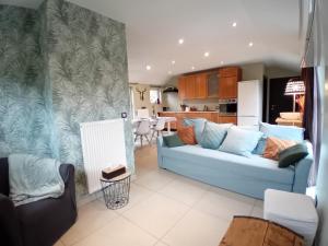 a living room with a blue couch and a kitchen at Le coin des évasions in Verviers