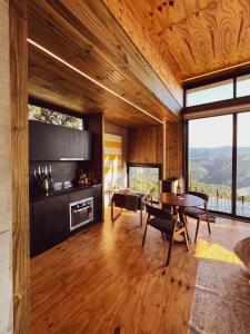 a living room with a table and chairs and windows at Cabanas Terrunyo - Cabana Bela in Urubici