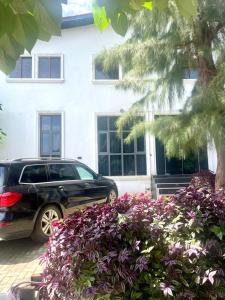 a car parked in front of a house with purple flowers at Wine House, Maitama, Abuja in Abuja