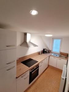 a kitchen with white cabinets and a stove top oven at Ferienwohnung Thomas Müntzer in Mühlhausen