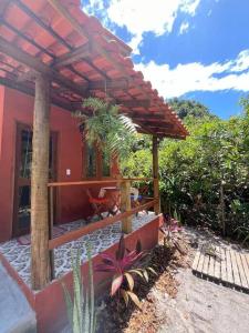 una casa rossa con un pergolato e alcune piante di Casinha Tupã cheia de charme a Mata de Sao Joao