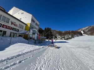 una persona parada en la nieve frente a un edificio en Lodge Iwakura Yamato, en Katashina