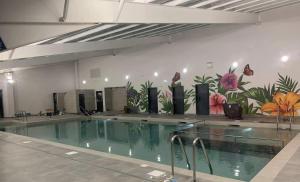 a swimming pool with a mural of flowers on the wall at Your Ultimate Holiday Rental at Pevensey Bay 35 Woodland Walk in Pevensey