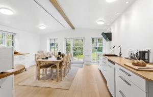 a kitchen with white cabinets and a table with chairs at Three-Bedroom Holiday Home In Tranekar in Østerhuse