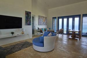 a living room with a blue chair and a tv at Experience mesmerizing views at The Cliff House from your private plunge pool in Aguadilla