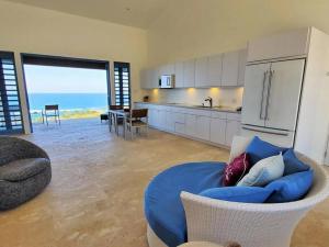 a living room with a blue couch and a kitchen at Experience mesmerizing views at The Cliff House from your private plunge pool in Aguadilla