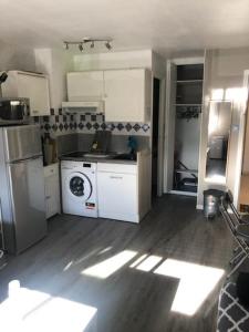 una cucina con armadietti bianchi e lavatrice di Asphodèle, Joli studio avec parking, 2 pas des plages et du Port a Cap d'Agde