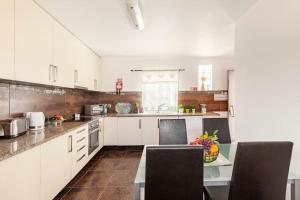 a kitchen with white cabinets and a table with chairs at Casa do Fontanário in Penafiel