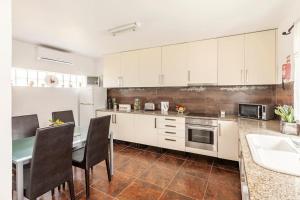 a kitchen with white cabinets and a table with chairs at Casa do Fontanário in Penafiel