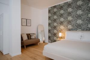 a bedroom with a white bed and a couch at Alatea Porta Nuova 20 in Verona