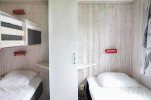 two beds in a room with wooden walls at Kvibergs Stugor - Cottages in Gothenburg