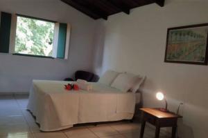 a bedroom with a white bed with a table and a window at Eco Suíte Jatobá Natureza Conforto e Paz in Pirenópolis