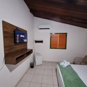 a bedroom with a bed and a tv on a wall at Eco Suíte Jatobá Natureza Conforto e Paz in Pirenópolis