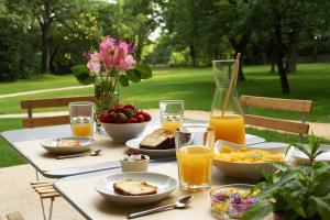 una mesa con alimentos para el desayuno y zumo de naranja en ella en Hôtel Les Esclargies en Rocamadour