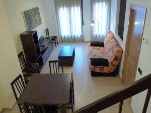 sala de estar con mesa, sofá y silla en Apartamentos Puerta Muralla, en Teruel