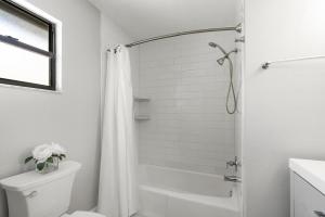 a white bathroom with a shower and a toilet at Beach Rd, 300ft to Beach Access & 500ft to Siesta Key Village, 2bdr in Siesta Key +25 photos