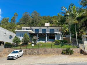 Un coche blanco aparcado delante de una casa en Casa com vista para o mar em Governador Celso Ramos, en Governador Celso Ramos
