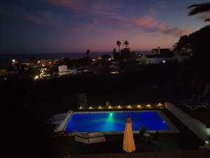 a swimming pool at night with a table and a umbrella at Villa Tranquilla in Estepona