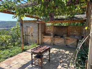 an outdoor kitchen with a wooden table and a grill at მყუდრო სახლი ფუნიკულიორის პარკთან in Okrokana