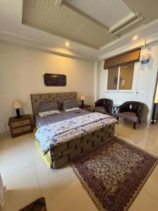a bedroom with a large bed and two chairs at Serenity Suites in Bhurban
