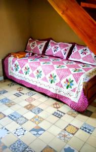 a bed with a quilt on top of a tiled floor at Los Laureles de Sorso in Villa Ciudad Parque