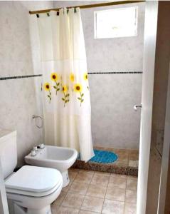 a bathroom with a toilet and a shower curtain with sunflowers at Los Laureles de Sorso in Villa Ciudad Parque