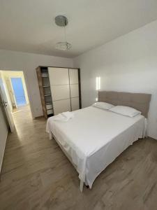 a bedroom with a large white bed and a wooden floor at SeaCharm in Dobra Voda