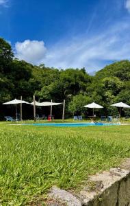 a swimming pool with chairs and umbrellas in a field at Reserva Pedra da Mata in Pelotas