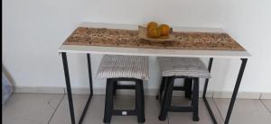 a table with two stools and a bowl of fruit at Ap Vila Tupi PG in Praia Grande