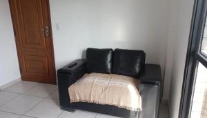 a black leather chair sitting next to a door at Ap Vila Tupi PG in Praia Grande