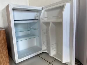 a white refrigerator with its door open in a kitchen at SUÍTES PÉ na AREIA ANGRA in Angra dos Reis