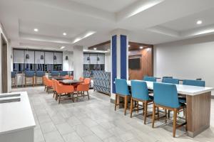 a dining room with chairs and tables and a cafeteria at Holiday Inn Express Hotel & Suites Winnie by IHG in Winnie