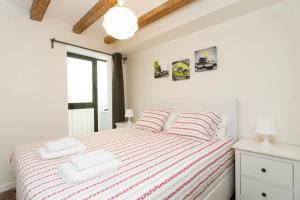 a white bedroom with a bed with striped sheets at Apartments Barcelona Sagrada in Barcelona