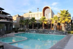 a swimming pool in front of a building with palm trees at Casa Allende Residencia en SMA in San Miguel de Allende +24 photos