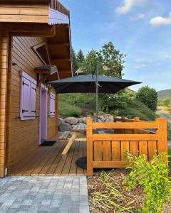 a wooden deck with a table and an umbrella at Chalet Le Montagnard SPA & SAUNA - Lits faits - Serviettes - Peignoirs - Ménage inclus in Rochesson