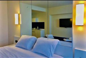 a bedroom with a white bed with a mirror at Orbi City - "A" in Batumi