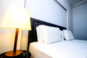 a lamp sitting next to a bed with white pillows at America Guest House in Lomé +37 photos