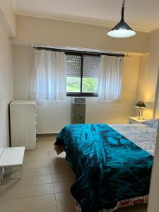 a bedroom with a blue bed and a window at Sol y Arena Plaza in San Clemente del Tuyú