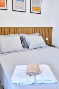 Una cama blanca con una toalla encima. en Studio Matira, próximo a praia, novo e moderno, en Ubatuba