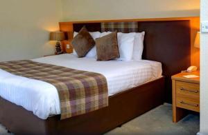 a hotel room with a large bed and a night stand at Buchanan Arms Hotel & Leisure, Sure Hotel Collection in Drymen +54 photos