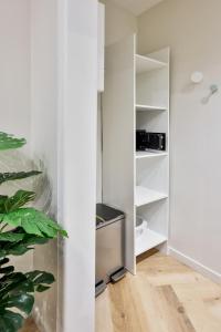 Zimmer mit weißen Wänden und weißen Regalen in der Unterkunft Le Chic & Biscornu - Terrasse - Clim - Centre Ville in Périgueux