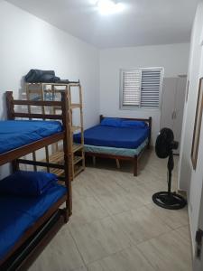 a room with three bunk beds and a fan at Apartamento Vista Mar Praia Grande, Ocian in Praia Grande