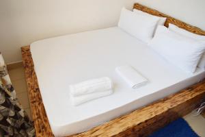 Una cama con sábanas blancas y dos toallas. en Tajari Diani Beach Condo, en Galu
