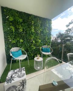 dos sillas y una mesa frente a una pared verde en KOAH LODGE Tahiti, en Papeete
