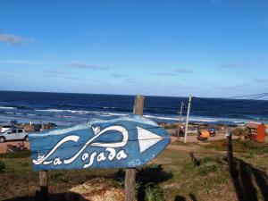 un cartel en la playa con el océano en el fondo en La Posada en Punta del Diablo